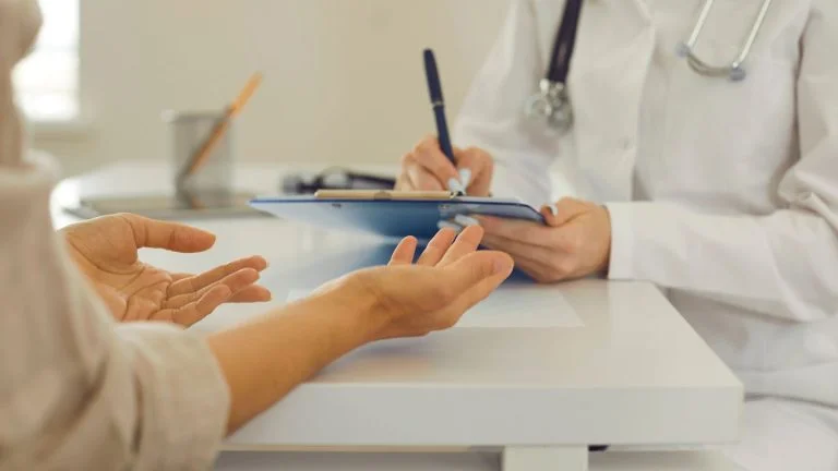 Patient Speaking with Doctor Taking Notes on Clipboard